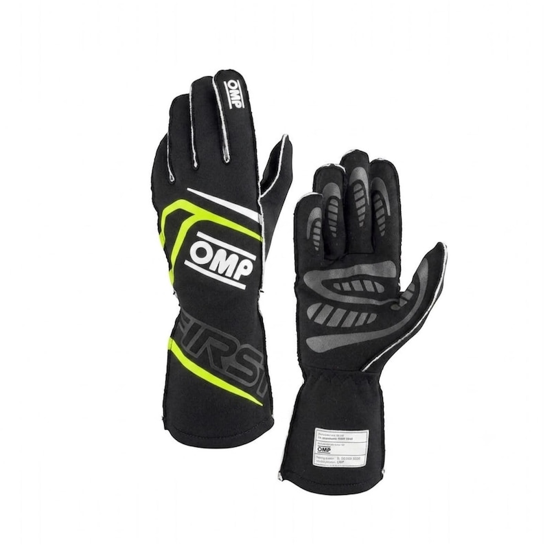 May include: A pair of black racing gloves with neon yellow accents and white OMP branding. The gloves feature a gauntlet cuff, a white OMP logo on the back of the hand, and grey textured grip patterns on the palm side with a white label on the cuff.
