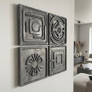Può includere: Un set di quattro piastrelle quadrate grigio scuro disposte in una griglia due per due. Ogni piastrella presenta un distinto design a rilievo, inclusi motivi geometrici, un motivo circolare e una forma floreale stilizzata con finitura opaca.