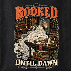 May include: A black t-shirt featuring a graphic illustration of a translucent ghost sleeping at a wooden desk in a library. The text BOOKED UNTIL DAWN is printed in orange. The scene includes stacks of books, a candle, and a window view of a sunset.