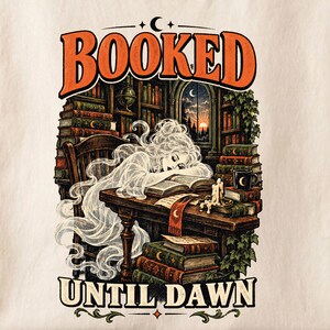 May include: A graphic print featuring the text BOOKED UNTIL DAWN with a translucent figure resting on an open book at a wooden desk. The scene includes stacks of vintage books, a lit candle, a mug, and a library background with a window view.