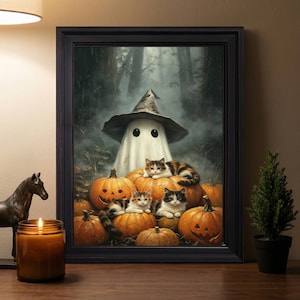 May include: A framed wall art print depicting a white ghost wearing a pointed hat standing behind several orange pumpkins. Three cats are resting on the pumpkins in a misty forest setting. The frame is black and rectangular with a simple border.