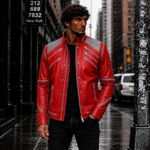 May include: A vibrant red leather jacket featuring a stand-up collar, multiple silver-toned diagonal zippered pockets on the chest, and grey textured shoulder panels. The jacket includes a central front zipper closure and additional zippers on the sleeves.