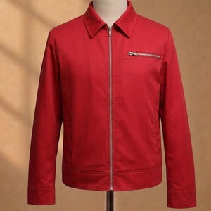 Op de afbeelding: Felrode jas met een kraag en een zilveren ritssluiting. Het heeft een klein ritsvakje op de borst. De jas wordt op een mannequin gepresenteerd.
