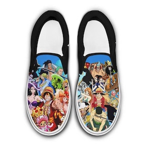 Pode incluir: Par de tênis slip-on pretos com uma estampa gráfica colorida de vários personagens de anime. Os sapatos têm sola branca com acabamento preto e cabedal preto.