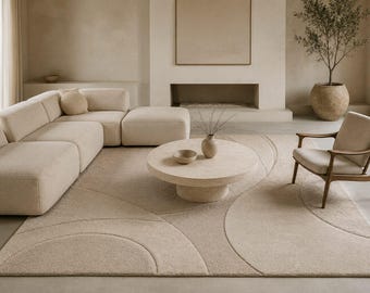May include: A large rectangular area rug in a neutral beige tone, featuring a textured surface with carved geometric semi-circle patterns. The rug is crafted with a thick, plush pile and covers a significant portion of the floor space in the room.