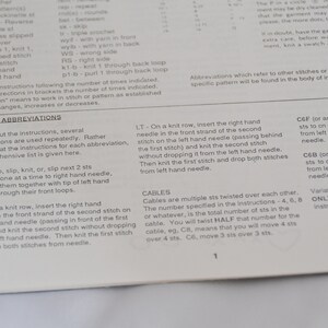 K&ouml;nnte beinhalten: Nahaufnahme einer Seite aus einem Strickmusterbuch. Die Seite zeigt eine Liste von Strickabk&uuml;rzungen und deren Definitionen. Der Text enth&auml;lt Begriffe wie "SSK", "RT", "LT", "CEF" und "C6B".