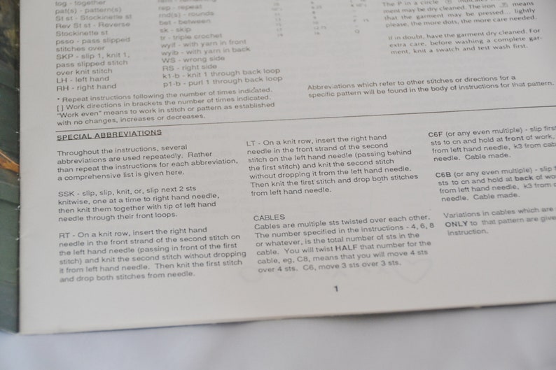 K&ouml;nnte beinhalten: Nahaufnahme einer Seite aus einem Strickmusterbuch. Die Seite zeigt eine Liste von Strickabk&uuml;rzungen und deren Definitionen. Der Text enth&auml;lt Begriffe wie "SSK", "RT", "LT", "CEF" und "C6B".