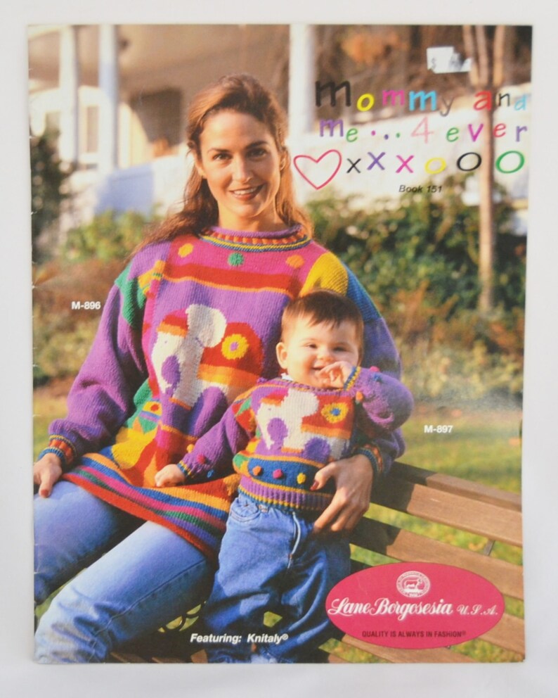 K&ouml;nnte beinhalten: Ein Strickmusterbuch mit einer Mutter und einem Kind, die farbenfrohe Pullover mit einem Hundemuster tragen. Der Buchumschlag tr&auml;gt den Titel "Mommy and Me... 4 ever" und den Text "Book 151".