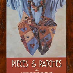May include: A pattern for a vest and necklace, titled "Pieces & Patches" and designed by Sandy Belt. The pattern is from Indygo Junction, Inc. The vest is made of patchwork fabric with a variety of colors and patterns, including brown, blue, and red. The necklace is made of brown and red buttons.