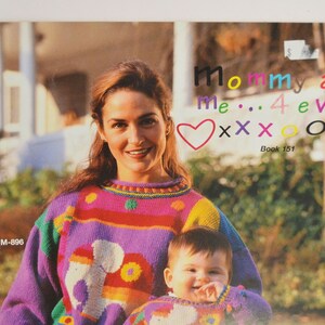 K&ouml;nnte beinhalten: Eine Frau und ein Kind tragen bunte Strickpullover mit einem Herz, Xs und Os. Der Text lautet "Mommy and me... 4 ever" und "Book 151".