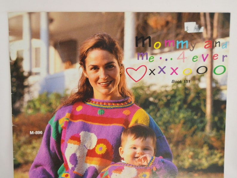 K&ouml;nnte beinhalten: Eine Frau und ein Kind tragen bunte Strickpullover mit einem Herz, Xs und Os. Der Text lautet "Mommy and me... 4 ever" und "Book 151".
