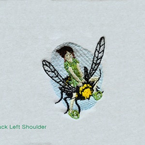 May include: Embroidered patch of a girl riding a bee with green wings and a yellow body. The girl is wearing a green shirt and has brown hair. The patch is on a white background.