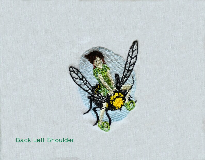 May include: Embroidered patch of a girl riding a bee with green wings and a yellow body. The girl is wearing a green shirt and has brown hair. The patch is on a white background.