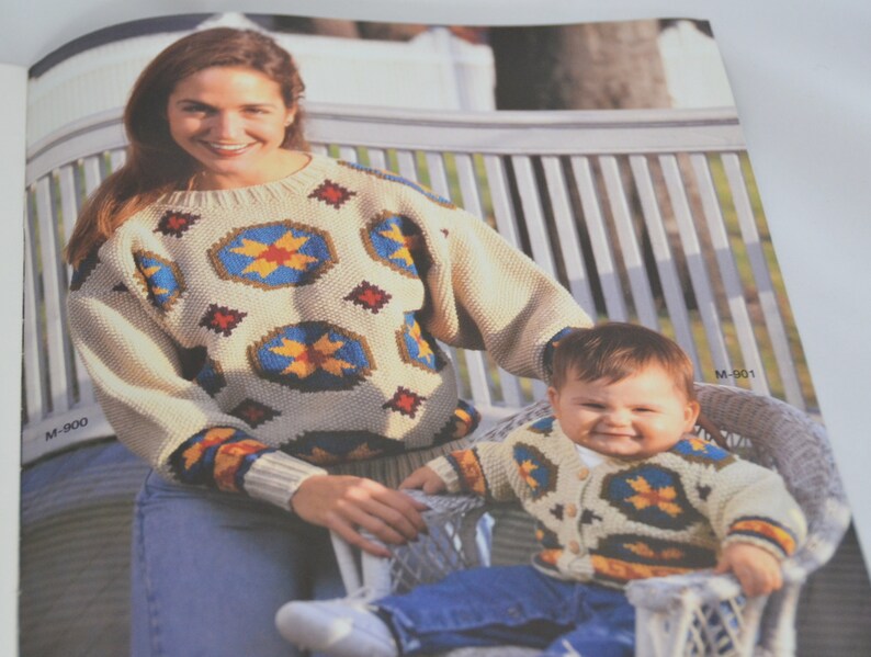 K&ouml;nnte beinhalten: Eine Frau und ein Kind tragen passende Pullover mit einem geometrischen Muster in Blaut&ouml;nen, Gelb, Rot und Braun. Die Pullover haben einen cremefarbenen Hintergrund. Die Frau tr&auml;gt eine blaue Jeans und das Kind tr&auml;gt eine blaue Jeans.