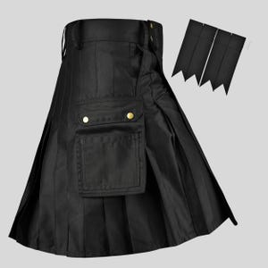 Peut inclure: Un kilt utilitaire noir avec un design plissé, une grande poche cargo sur le devant dotée de deux boutons-pression métalliques dorés, et une paire assortie de jarretières en tissu noir aux extrémités pointues située en haut à droite.