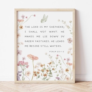 May include: A rectangular wall art print in a light wood frame featuring the text THE LORD IS MY SHEPHERD; I SHALL NOT WANT. HE MAKES ME LIE DOWN IN GREEN PASTURES. HE LEADS ME BESIDE STILL WATERS. PSALM 23:1-2 surrounded by watercolor flowers.