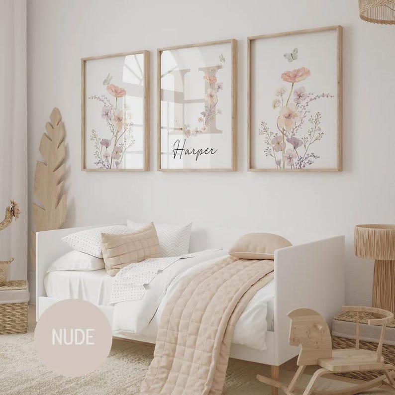 May include: Three framed floral art prints with a light wood finish. The prints feature watercolor flowers in soft pinks and purples, with a butterfly accent. The middle print has the name "Harper" in script.