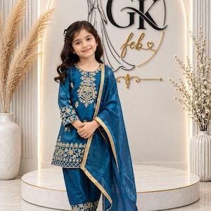 Könnte beinhalten: Ein dreiteiliges Outfit in Petrolblau, bestehend aus einer langärmeligen Tunika, einer passenden Hose und einem transparenten Dupatta. Die Tunika und die Hose sind mit aufwendigen goldenen Stickereien am Ausschnitt, an den Ärmelbündchen und am Saum verziert.