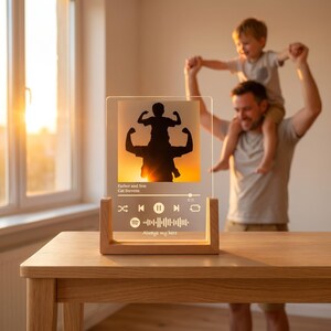 May include: A rectangular clear acrylic plaque set in a light wood base. The plaque features a printed silhouette of a parent and child, the text "Father and Son", "Cat Stevens", and "Always my hero", along with music player control icons.
