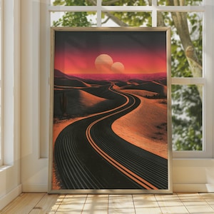 Könnte beinhalten: Ein gerahmter Wandkunstdruck mit einer kurvenreichen schwarzen Asphaltstraße, die durch eine Wüstenlandschaft mit hügeligen Sanddünen unter einem leuchtend roten und orangefarbenen Sonnenuntergangshimmel mit zwei großen Sonnen am Horizont führt.
