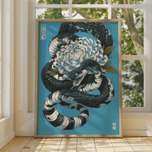 May include: A framed art print on a blue background featuring a coiled black and white snake with an open mouth and a large white chrysanthemum flower. The print includes a vertical column of three small square symbols and Japanese text characters.