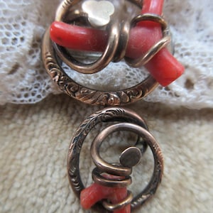 Puede incluir: Un par de broches antiguas de tono dorado con acentos de coral rojo. Cada broche presenta un marco circular con un dise&ntilde;o intrincado y un alambre retorcido que sostiene una pieza de coral.