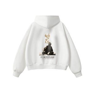 May include: White hoodie with a hood and long sleeves. The back features a graphic of a person and text in gold, with the word "FORTITUDE" below. The phrase "LIFE IS FOR THOSE WHO DARE" is also printed on the hoodie.