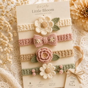 May include: A set of four crochet headbands on a display card labeled Little Bloom. The headbands feature floral and bow designs in cream, dusty pink, and sage green, with intricate petal, leaf, and berry details. A tag reads Made with love.