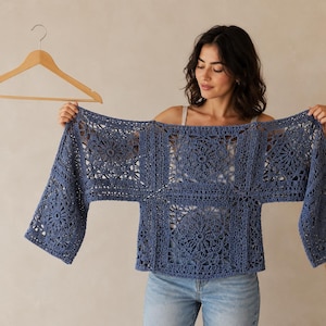 Könnte beinhalten: Ein blaues Häkeloberteil mit einem quadratischen Blumenmuster, weiten Ärmeln und einem durchbrochenen Design. Das Kleidungsstück besteht aus mehreren miteinander verbundenen quadratischen Paneelen mit aufwendigen Maschen.