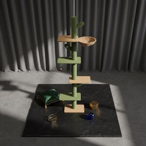 Peut inclure: Un arbre &agrave; chat vert et beige avec une conception en forme de cactus, des plateformes et un panier en osier. L'arbre &agrave; chat est sur une surface noire avec un coussin vert, un objet g&eacute;om&eacute;trique dor&eacute; et une sph&egrave;re de verre bleue.