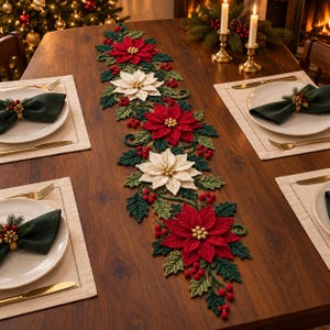 Pode incluir: Um longo caminho de mesa de crochê com um padrão repetitivo de flores de poinsétia vermelhas e brancas, folhas de azevinho verde-escuras e pequenas bagas vermelhas. O caminho está centrado numa mesa de madeira com pratos brancos, guardanapos e talheres.