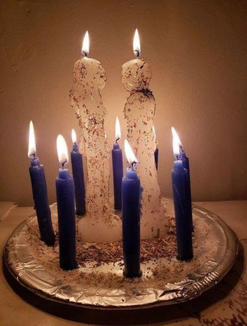 A silver tray holds nine lit candles in various sizes, arranged in a circular pattern.
