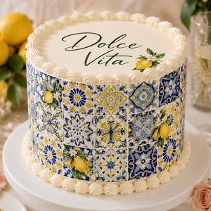 Peut inclure: Un gâteau rond avec une base de glaçage blanc, décoré d'un motif de carreaux bleus, jaunes et blancs. Le gâteau est surmonté des mots "Dolce Vita" en écriture verte et d'une illustration de citron. Il repose sur un présentoir à gâteau blanc.