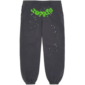 May include: Dark gray sweatpants with the word "reggas" in bright green, accented with white, green, and black star graphics. The sweatpants have an elastic waistband and cuffs, and pockets on the sides.