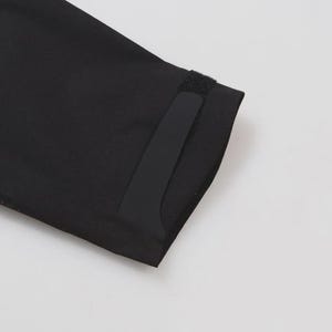 May include: Close-up of a black fabric sleeve with a velcro closure. The sleeve is angled, showing the edge and a portion of the cuff. The background is plain white.