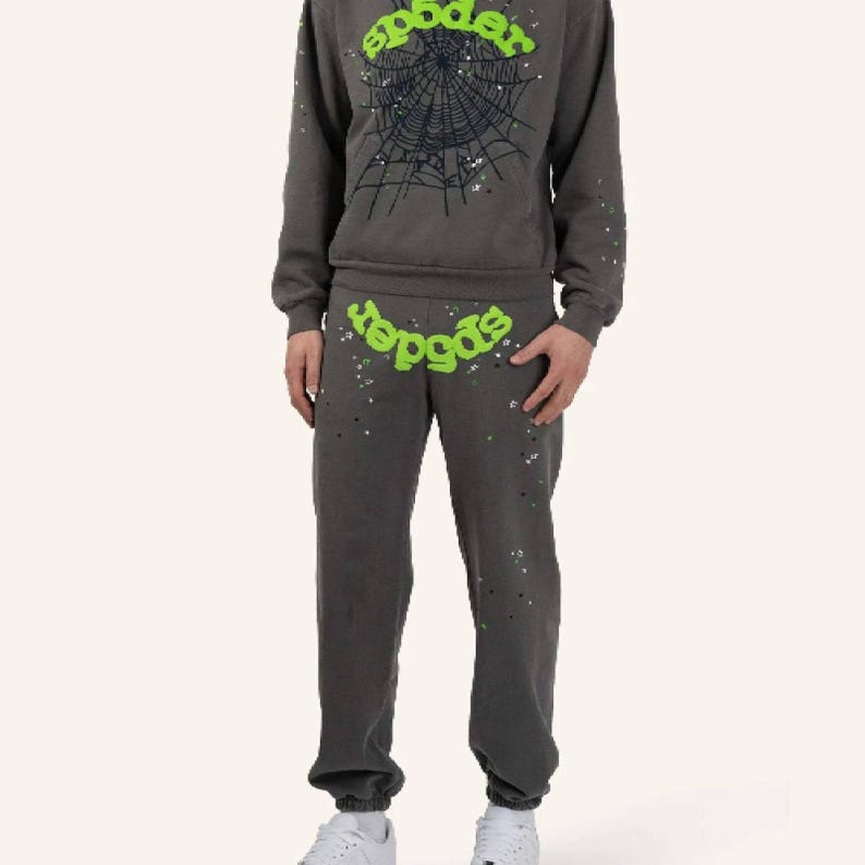May include: A gray sweatsuit with the word "spider" in green, and a spiderweb graphic on the sweatshirt. The sweatpants and sweatshirt have a speckled design. The person is wearing white sneakers.