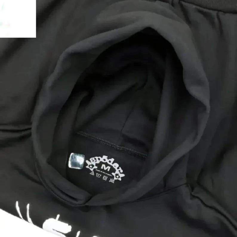 Pu&ograve; includere: Felpa con cappuccio nera con coulisse. La felpa presenta un emblema bianco con la lettera "M" al centro. Il cappuccio &egrave; aperto, rivelando l'interno del capo. La felpa &egrave; realizzata in un materiale morbido.