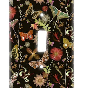 May include: A black light switch cover with a pattern of butterflies, flowers, and leaves in shades of brown, red, and green.