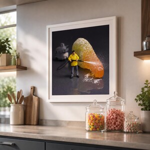 Puede incluir: Un cuadro decorativo enmarcado que muestra una figura en miniatura con chaqueta amarilla usando una hidrolimpiadora para limpiar una golosina de goma naranja recubierta de az&uacute;car sobre un fondo oscuro, creando una escena creativa.