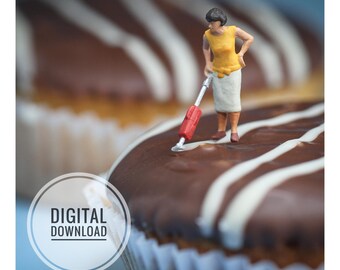 Puede incluir: Una figura en miniatura de una persona con top amarillo y falda blanca, usando una aspiradora roja y plateada sobre un cupcake cubierto de chocolate con hilos de glaseado blanco. La imagen incluye el texto MINIMANI.BE y DIGITAL DOWNLOAD.