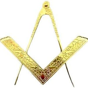 Könnte beinhalten: Ein goldfarbenes metallenes Freimaurer-Emblem aus Winkel und Zirkel mit detaillierten, geprägten Rankenmustern entlang der Winkelschenkel und Zirkelbeine sowie einem kleinen kreisförmigen Gelenk an der Spitze, das beide Teile verbindet.