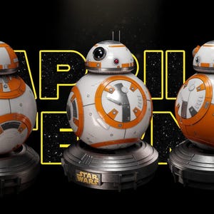 May include: Three spherical white and orange droid figures with domed heads and antennas, each mounted on a circular dark gray base. The central droid features a prominent black circular eye lens. The background displays the text STAR WARS.