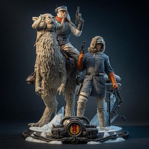 May include: A detailed collectible statue featuring a figure riding a shaggy, horned creature and a second standing figure. Both figures wear cold-weather gear, including parkas and hoods. The base displays a circular emblem with a red and yellow symbol.