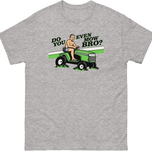 May include: A heather gray t-shirt featuring a graphic of a person driving a green riding lawn mower. The text "DO YOU EVEN MOW BRO?" is printed in black above the mower, with a green horizontal stripe behind the illustration of the mower.