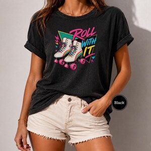 A woman wearing a black t-shirt with a graphic design of rollerblades and the text "Roll with it" printed on it.