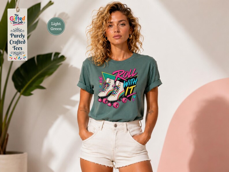 A woman wearing a green t-shirt with a graphic of rollerblades and the text "Roll with it" stands in front of a pink wall.