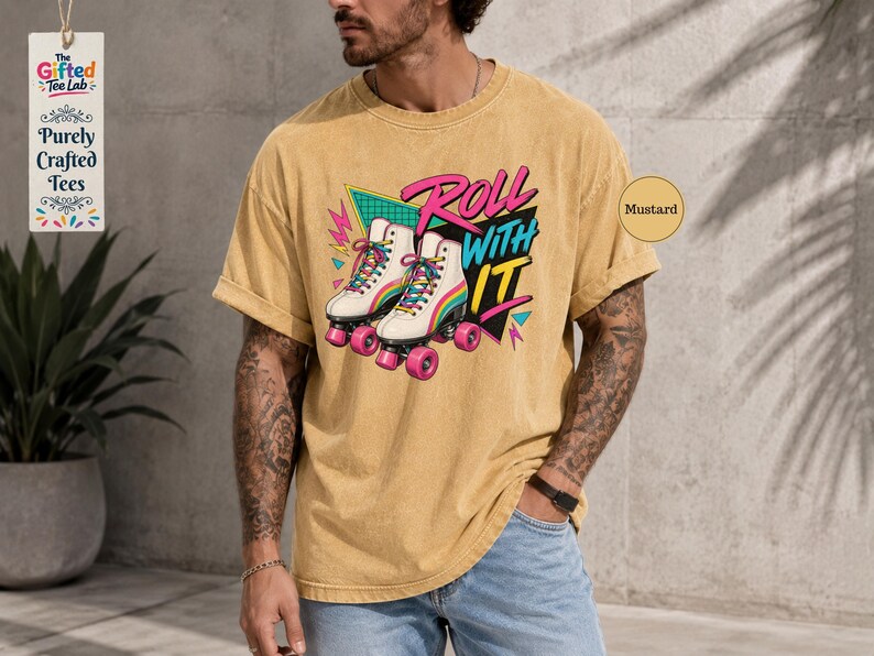 A man wearing a yellow t-shirt with a graphic of roller skates and the text "Roll with it" is standing in front of a concrete wall.