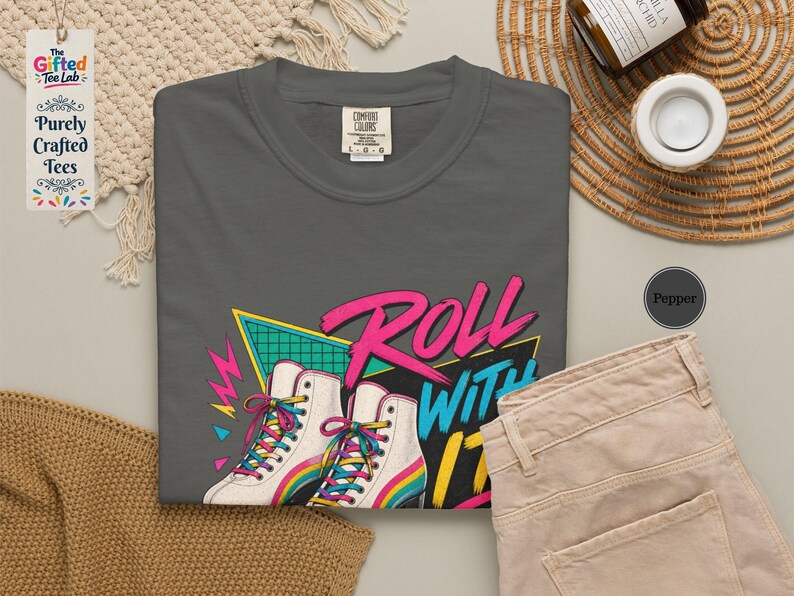 a variety of items, including a black t-shirt with a graphic design, a hat, a wooden box, a notebook, a pen, a cup, a bowl, and some dried flowers.