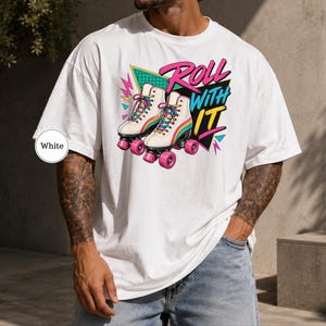 A man wearing a white t-shirt with a graphic design of roller skates and the text "Roll with it" printed on it.