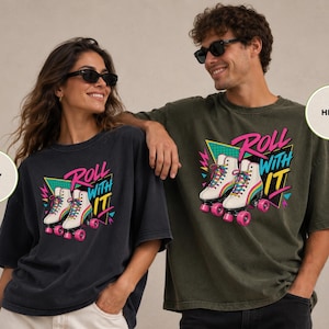 A woman and a man are posing together, both wearing t-shirts with a graphic design featuring rollerblades and the text "Roll with it".